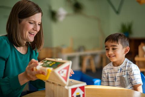 photo of teacher and young student with wooden toy