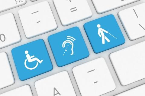 Close up view of a computer keyboard. Three keys are light blue. One has a symbol of a person in a wheelchair. One has a symbol for assistive listening. One has a symbol of a person walking with a cane.