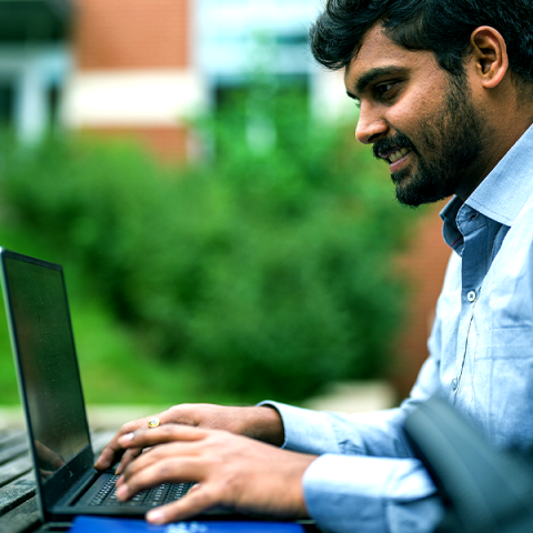 UNH student working on laptop outside
