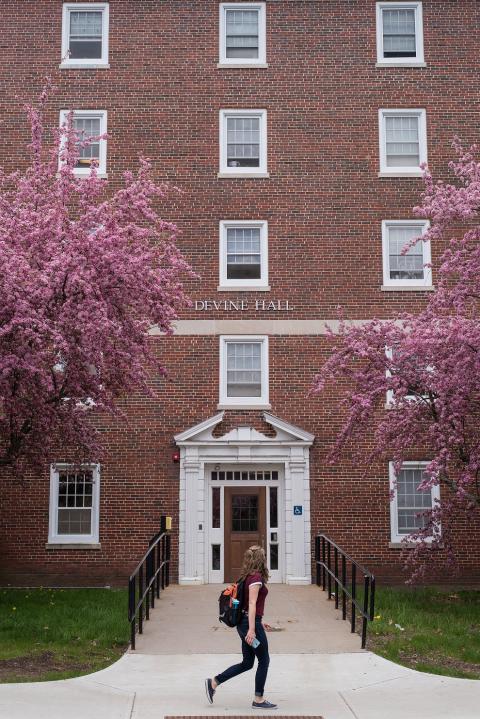 Student walking past Devine Hall