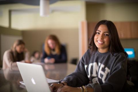 Student smiling and working on laptop