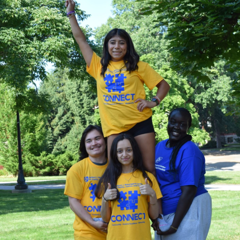 Three CONNECT students holding one student up with their fist in the air