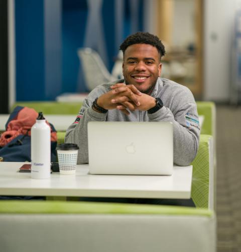 ECEnter student working at a laptop in a colorful table and chair booth