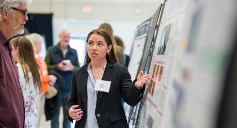 Student presenting research poster to professor
