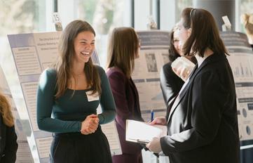 UNH student and professor conversing in front of UNH Undergraduate Research Conference presentation