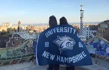 Students studying abroad with UNH blanket draped around their shoulders