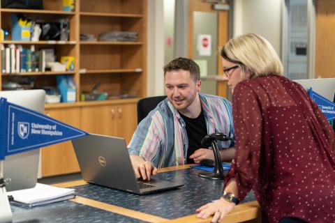 Two people looking at computer in library