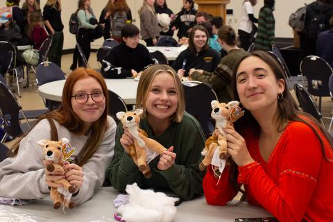 Three students holding up stuffed deer craft.