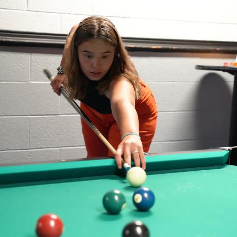 Student lining up for shot on billiards table in the MUB Games Room.