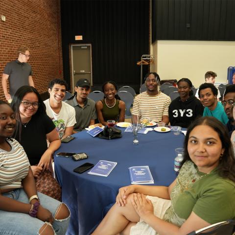 Student org sitting at table smiling at camera.
