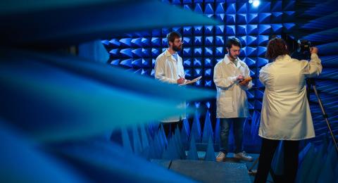 Three researchers stand in blue anechoic chamber