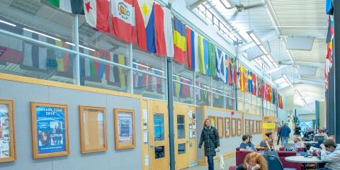 Students studying at tables near international flags hanging on the walls