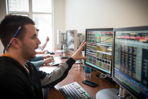 Student studying code and graphs on computer screens