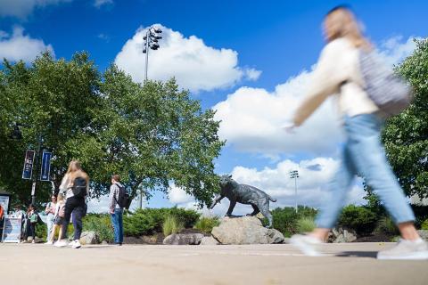 Students walking in a blur past the UNH Wildcat statue