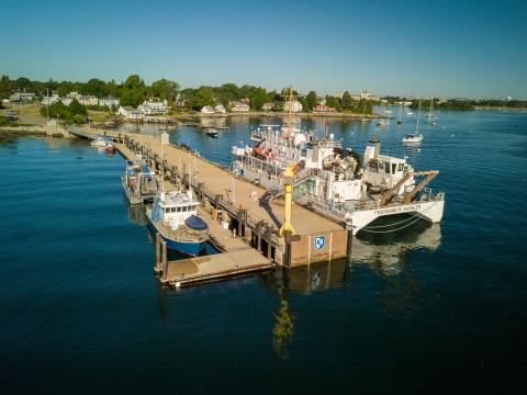 Drone shot of UNH pier, with small vessels and large NOAA ship