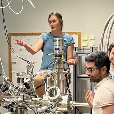 Female physicist speaking in lab behind equipment