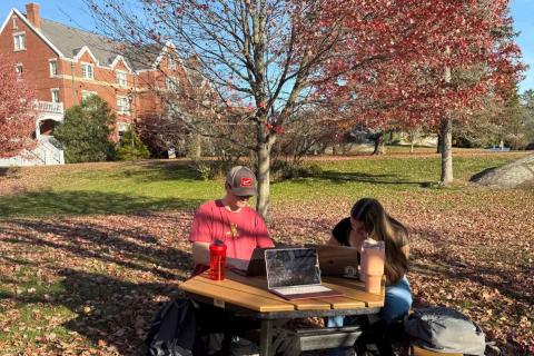 UNH students working at picnic table outside