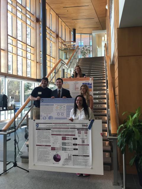 Students standing on staircase with ribbon-winning research posters