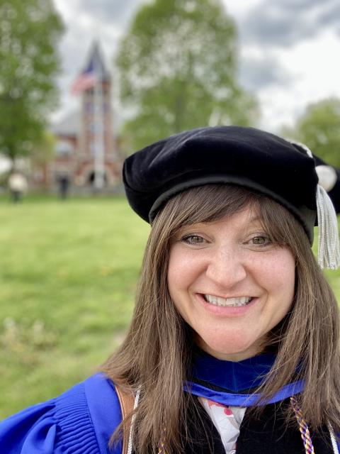 photo of Meaghan in full regalia in front of Thompson Hall at UNH