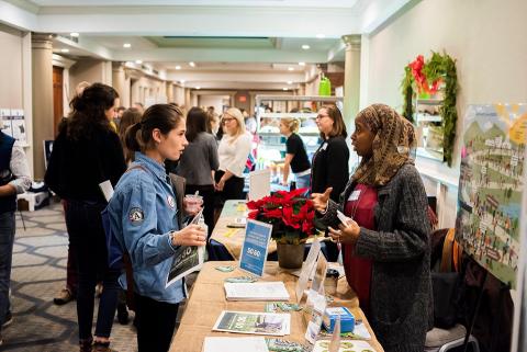 Food Solutions New England volunteer talking to student at tabling event.