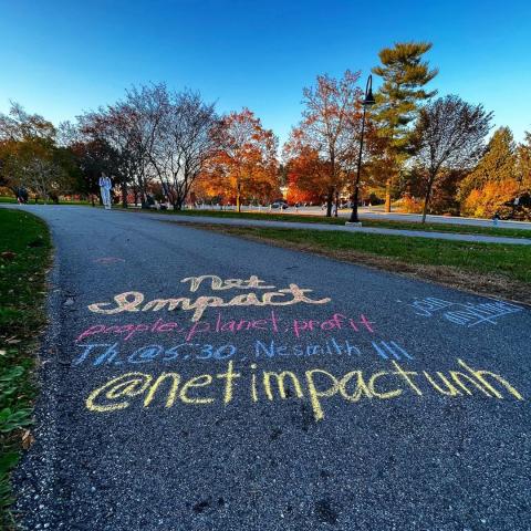 sidewalk with chalk writing with time and location of UNH Net Impact meetings