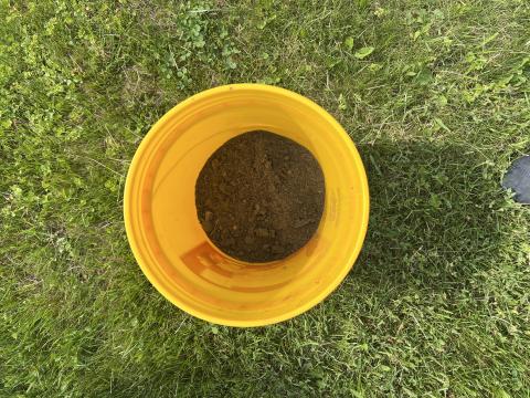 Overhead view of a yellow bucket with soil inside of it