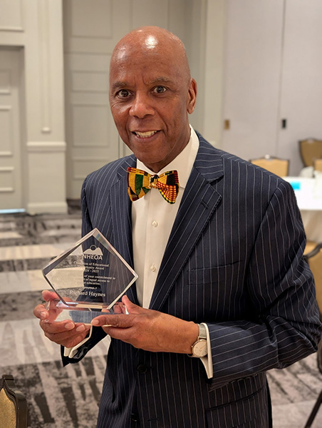 Man in suit and bow tie holding glass award