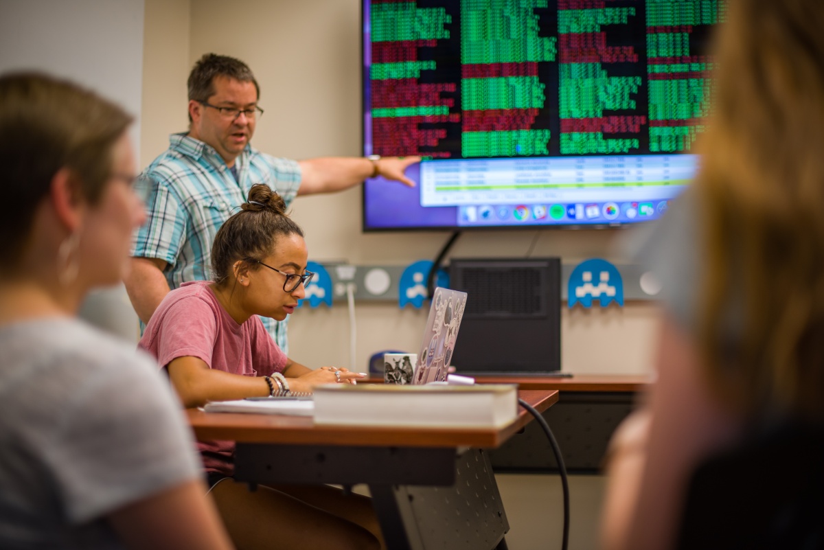 Professor and student reviewing data projected on a screen