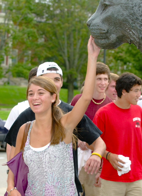 UNH student patting the Wildcat statue's nose