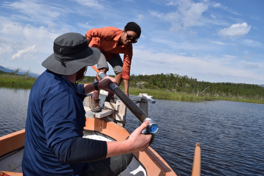 On a boat on a lake, two graduate students hold a research instrument