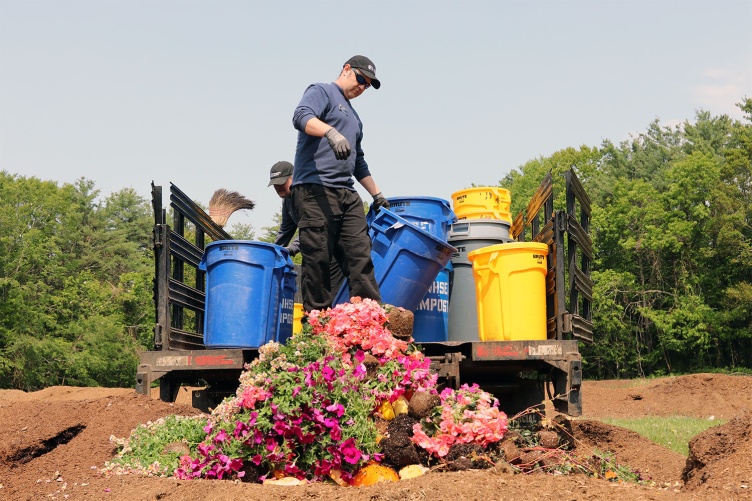 A photo of UNH Dining Services staff members unloading buckets full of compost at the Kingman Research Farm.