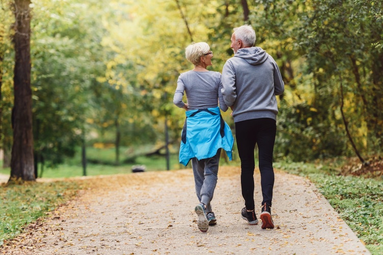 A man and a woman, shot from behind, walk along a path.