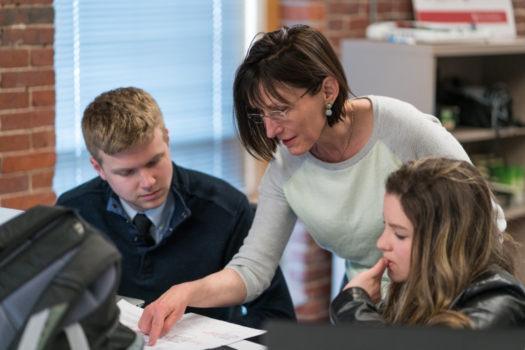 Female professor leans over two college students