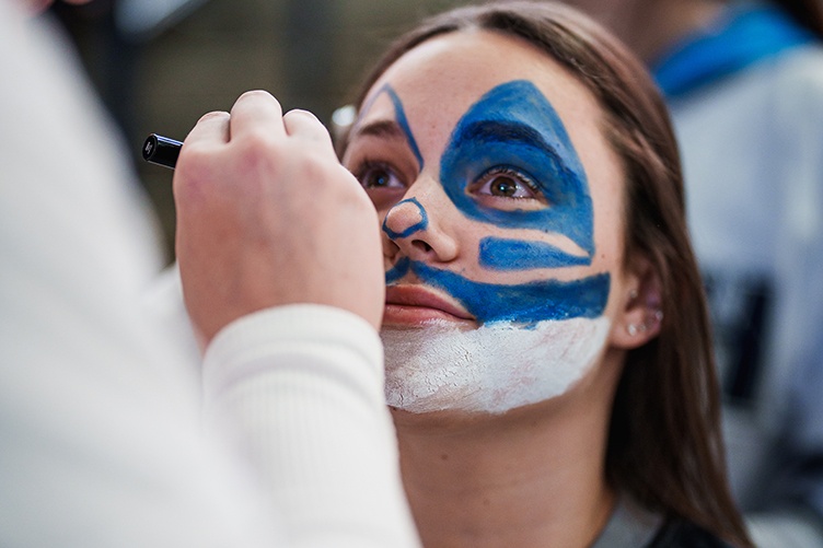 Female student getting her face painted at a hockey game