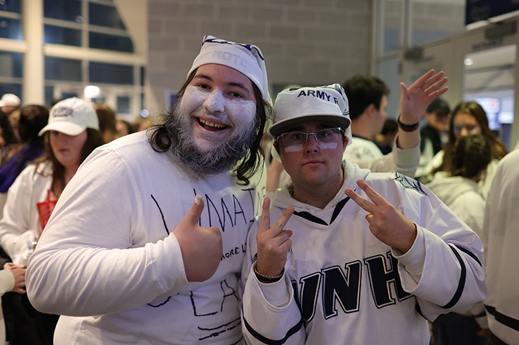 Two male students pose for a photo entering a hockey game