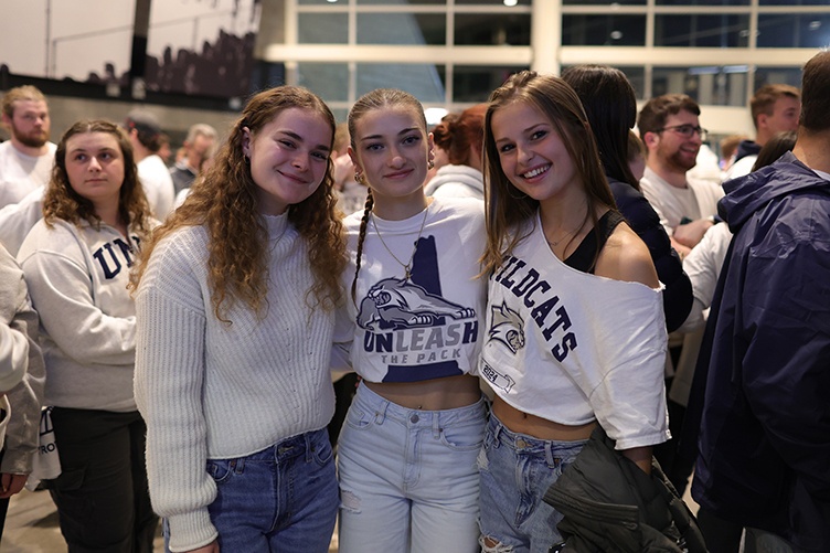 Three female students pose for a photo entering a hockey game