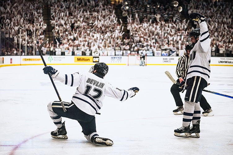 A UNH hockey player celebrates a goal in front of excited fans