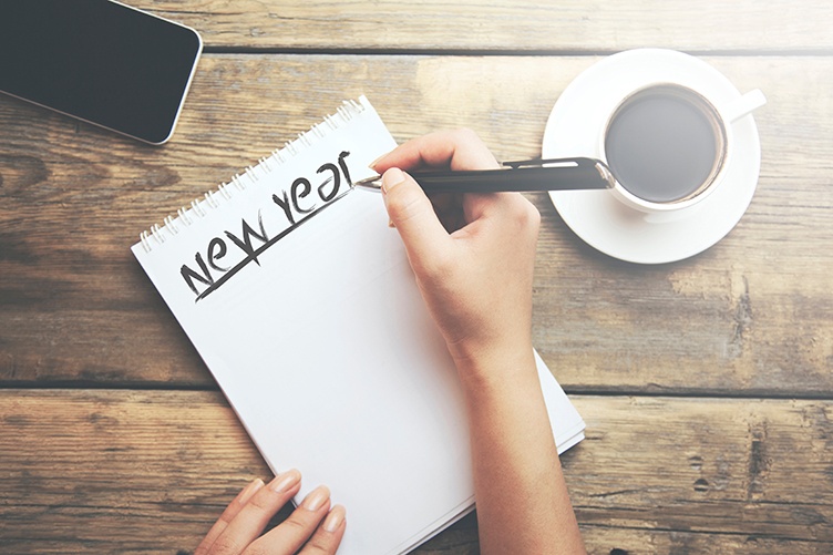 Overhead view of person writing resolution list on desk next to coffee cup