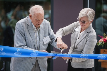 Man and woman cut a ribbon with giant scissors