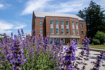 a photo of Paul College building with purple flowers framing the shot