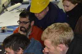 Jonathan Beaudoin (in glasses and orange sweater), research assistant professor in the University of New Hampshire’s Center for Coastal and Ocean Mapping/Joint Hydrographic Center, views the underwater footage of the S.S. Terra Nova with others onboard the Schmidt Ocean Institute’s R/V Falkor.