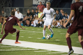 A member of the men's soccer team moves the ball downfield. 