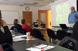 an instructor shows a colorful biology slide at the front of a classroom