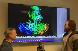 Rick Cote and Michael Irwin look at a model of the activated complex of the enzyme PDE6 dimer.