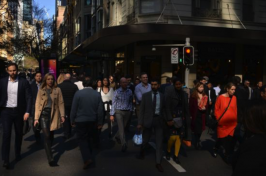 Women and men of different backgrounds cross a busy street in a city.