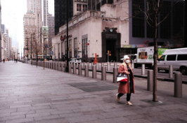 A single woman walks down an empty New York City street in a mask