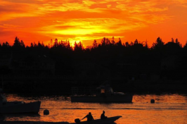 A lobsterman and his crew member head out to his fishing boat as the sun rises over Bass Harbor on Mount Desert Island.