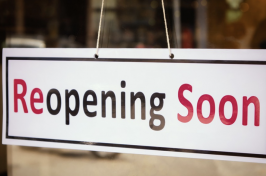 Picture of a sign hanging on a door that says "reopening soon"