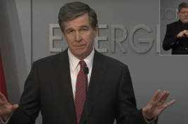 A photograph of North Carolina Governor Roy Cooper during a press conference.