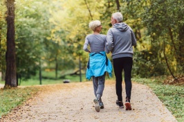 A man and a woman, shot from behind, walk along a path.